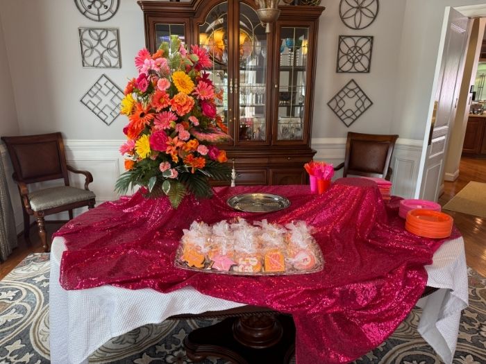 Vibrant floral arrangement in shades of hot pink, orange, and yellow displayed on a sequin-covered dessert table by Simply LaMayed Custom Decor.