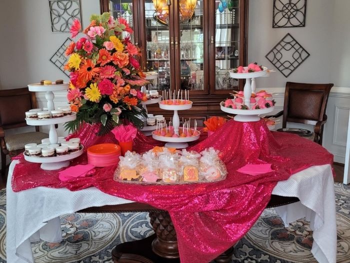 Hot pink sequin dessert table with floral centerpiece, cookies, and treats designed for a bright celebration by Simply LaMayed.