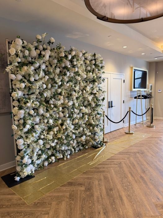 White floral backdrop with gold carpet aisle and rope stanchions, available for rent from Simply LaMayed for upscale events in Northern Virginia.