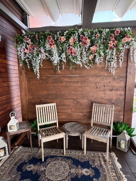 Wood backdrop with cascading floral installation and seating area, perfect for photo booths or event lounges, available from Simply LaMayed Rentals.